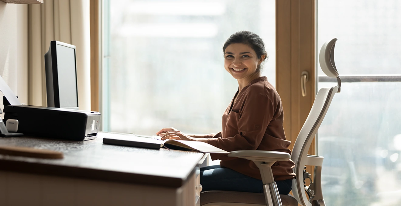 Une conseillère en prévention analyse un poste de travail avec un employé dans un bureau attenant à un entrepôt.